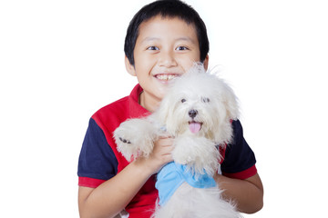 Little boy hugging Maltese dog on studio