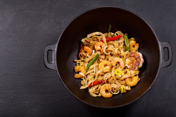 Stir fried noodles with shrimps and vegetables in a wok