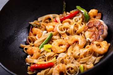 Stir fried noodles with shrimps and vegetables in a wok