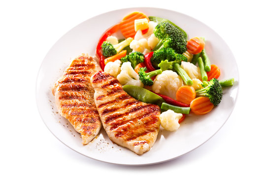 plate of grilled chicken with vegetables on white background