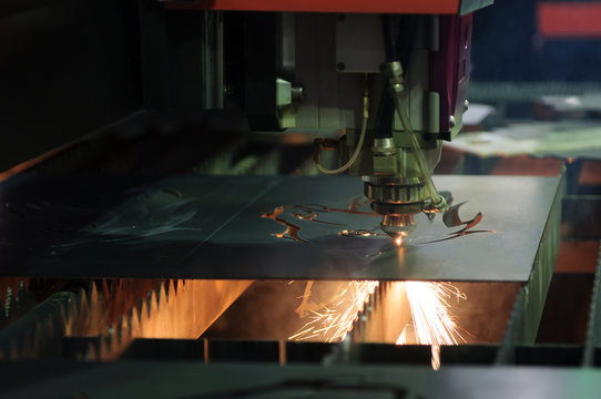 The CNC laser cut machine while cutting the sheet metal with the sparking light.