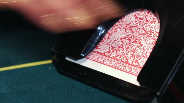 Dealer in casino deals the cards by the card feeder.