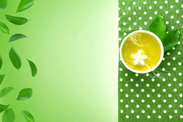 Top view shot of a hot cup of tea with green leaf decoration  with green napkin on green background , Organic green Tea ceremony time concept