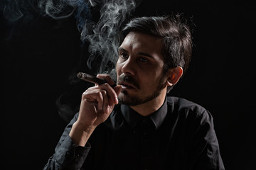 Portrait of adult man who is smoking cigar.