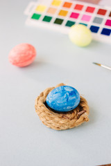 Deep blue easter egg on nest over bright background.