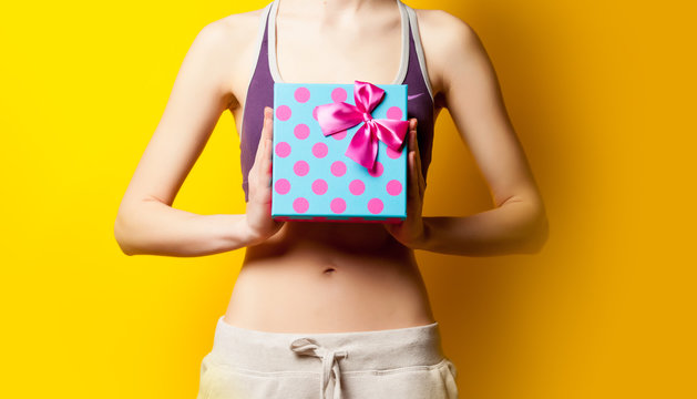 photo of perfect slim female body with cute gift in the hands on the wonderful yellow background