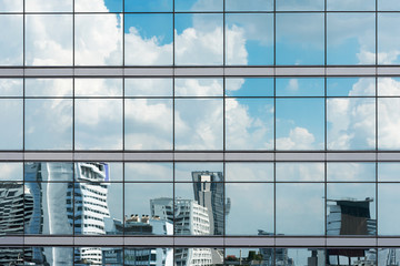 Obraz premium Cloud reflection in high glass offices. Blue reflection of the sky. Windows of a building. Business background. Business construction.