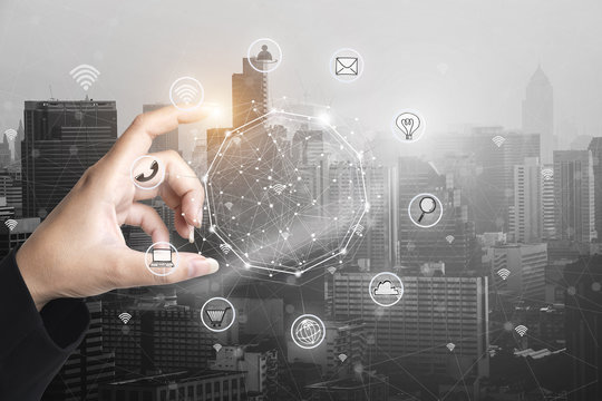 Businessman holding smart phone with wireless communication network icon and cityscape background.E-commerce smart connection business. internet of things.