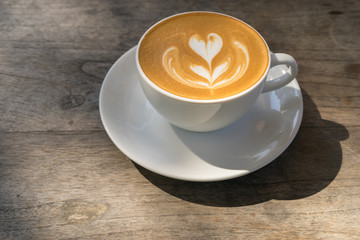 Top view hot latte coffee in white cup on vintage wooden table background, Natural light, Vintage Tone