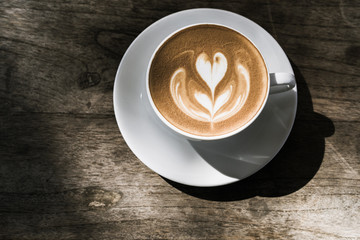 Top view hot latte coffee in white cup on vintage wooden table background, Natural light, Vintage Tone