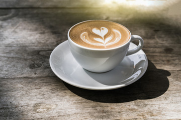 Hot latte coffee in white cup on vintage wooden table background, Natural light, Vintage Tone