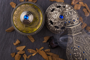 Silver Oriental Artisitc Arabian Oud Perfume / Arabian Oud Perfume with Oud Scented Wood burned in the background with Scented Smoke in the Air 
