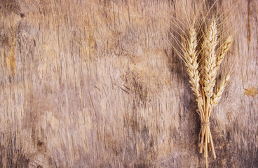 A bunch of wheat spikes on an old wooden background. Copy space