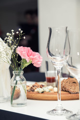 Close up picture of wine glasses with flower and empty glasses in restaurant. Serving table prepared for event party or wedding. Soft focus, selective focus. Toned.