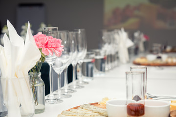 Close up picture of wine glasses with flower and empty glasses in restaurant. Serving table prepared for event party or wedding. Soft focus, selective focus. Toned.
