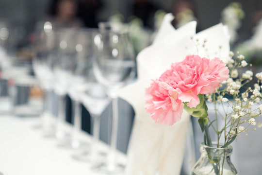 Close up picture of wine glasses with flower and empty glasses in restaurant. Serving table prepared for event party or wedding. Soft focus, selective focus. Toned.