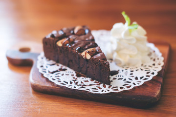 A piece of brownie cake and whipped cream in wooden plate on wooden table