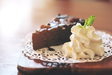 A piece of brownie cake and whipped cream in wooden plate on wooden table
