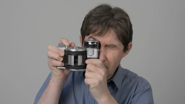 Man photographer takes pictures of an old panoramic photo camera. Adult male with a camera on a light background