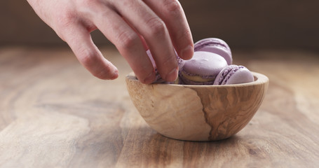 Obraz na płótnie Canvas man hands filling bowl with lavender violet macarons, 4k photo