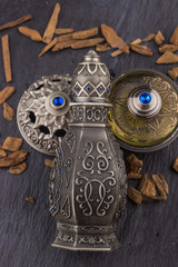 Silver Oriental Artisitc Arabian Oud Perfume / Arabian Oud Perfume with Oud Scented Wood burned in the background with Scented Smoke in the Air 
