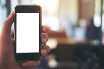 Mockup image of hand holding black mobile phone with blank white screen in cafe