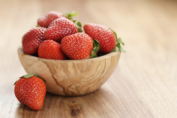 fresh strawberries in bowl on wood table with copy space, organic garden berries