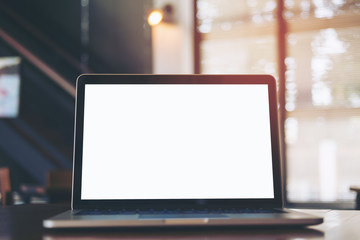 Mockup image of laptop with blank white screen on wooden table in modern loft cafe