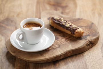fresh espresso and eclair with hazelnuts, sweet morning breakfast