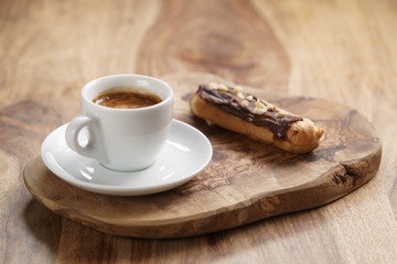fresh espresso and eclair with hazelnuts, sweet morning breakfast