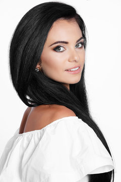 Beautiful brunette woman smiling on white background. Beauty model girl with long dark hair, clean skin and perfect smile isolated. Beauty and skin care concept.