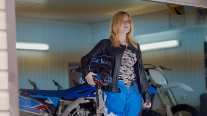 Woman MXgirl with motocross helmet in the garage