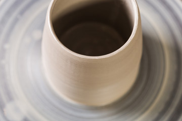 Creating mug from clay on a twisted potter's wheel close up. Macro. Blurred mug from clay on a twisted potter's wheel with empty space for the text. Handmade concept.