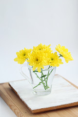 bouquet of yellow Chrysanthemum flowers in glass on table, abstract light background. floral gift. festive composition with flowers. template for design