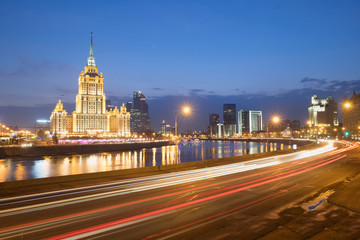 Blurred night traffic movement lights at the center of Moscow, aerial urban view with Stalin Skyscraper and its reflection in the Moscow River, outdoor travel background