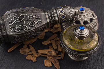 Silver Oriental Artisitc Arabian Oud Perfume / Arabian Oud Perfume with Oud Scented Wood burned in the background with Scented Smoke in the Air 