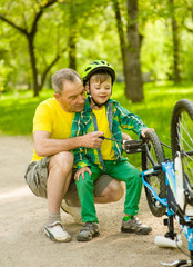 Fototapeta premium Grandson with his grandfather pumped wheel bicycle