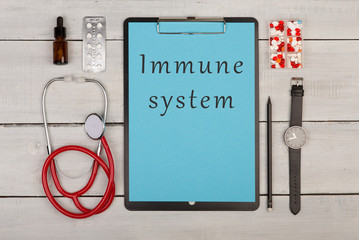clipboard with text "Immune system", pills, stethoscope and watch