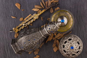 Silver Oriental Artisitc Arabian Oud Perfume / Arabian Oud Perfume with Oud Scented Wood burned in the background with Scented Smoke in the Air 