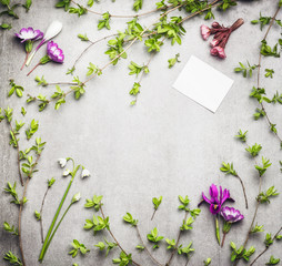 Springtime nature frame with spring twigs and flowers and blank white paper card, top view