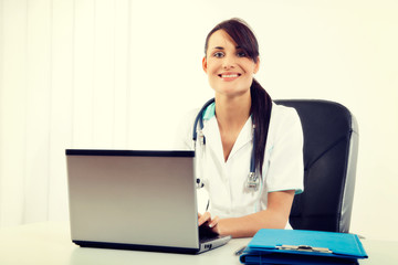 Female doctor sitting at office desk and smiling at camera