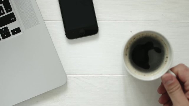 Man working on a wooden table with laptop and drink coffe, top view, cpop shot