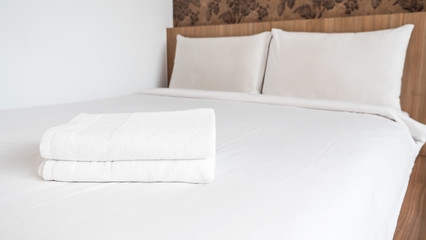 Two white laundered fluffy towels on white bed 1