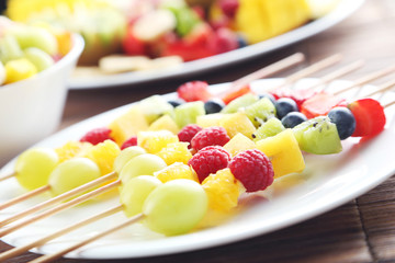 Fresh fruit on skewers on a brown wooden table