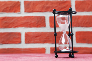 Black hourglass on the brick wall background