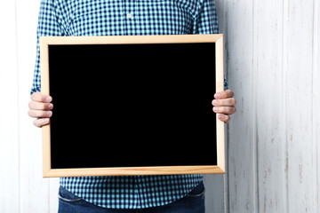 Male hands holding wooden frame on wall paneling background