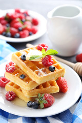 Homemade waffles with berries in plate on grey table