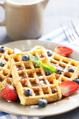 Homemade waffles with berries in plate on grey table