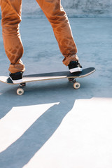 Fototapeta premium Close up of skater's legs in black sneakers on a skateboard in a concrete skatepark