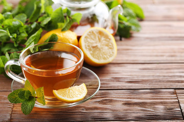 Cup of tea with mint and lemon on brown wooden table